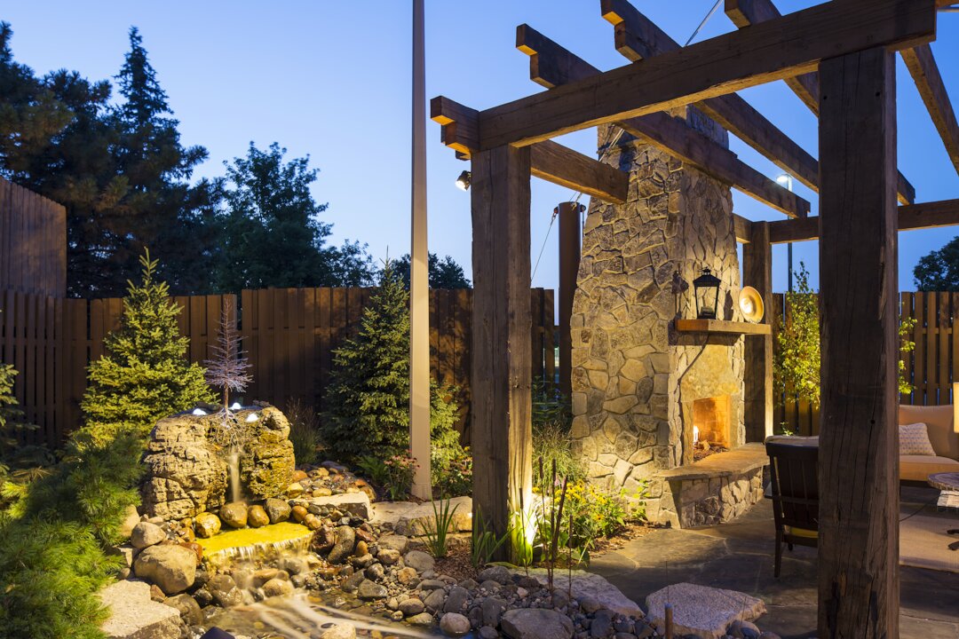 Outdoor patio with stone fireplace and water feature.