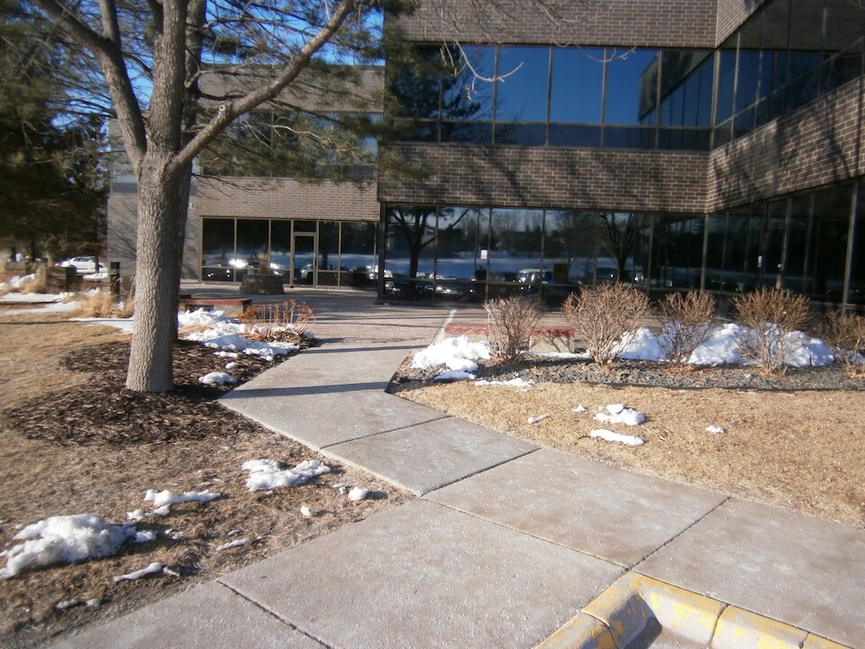 Pathway in winter beside glass office building.