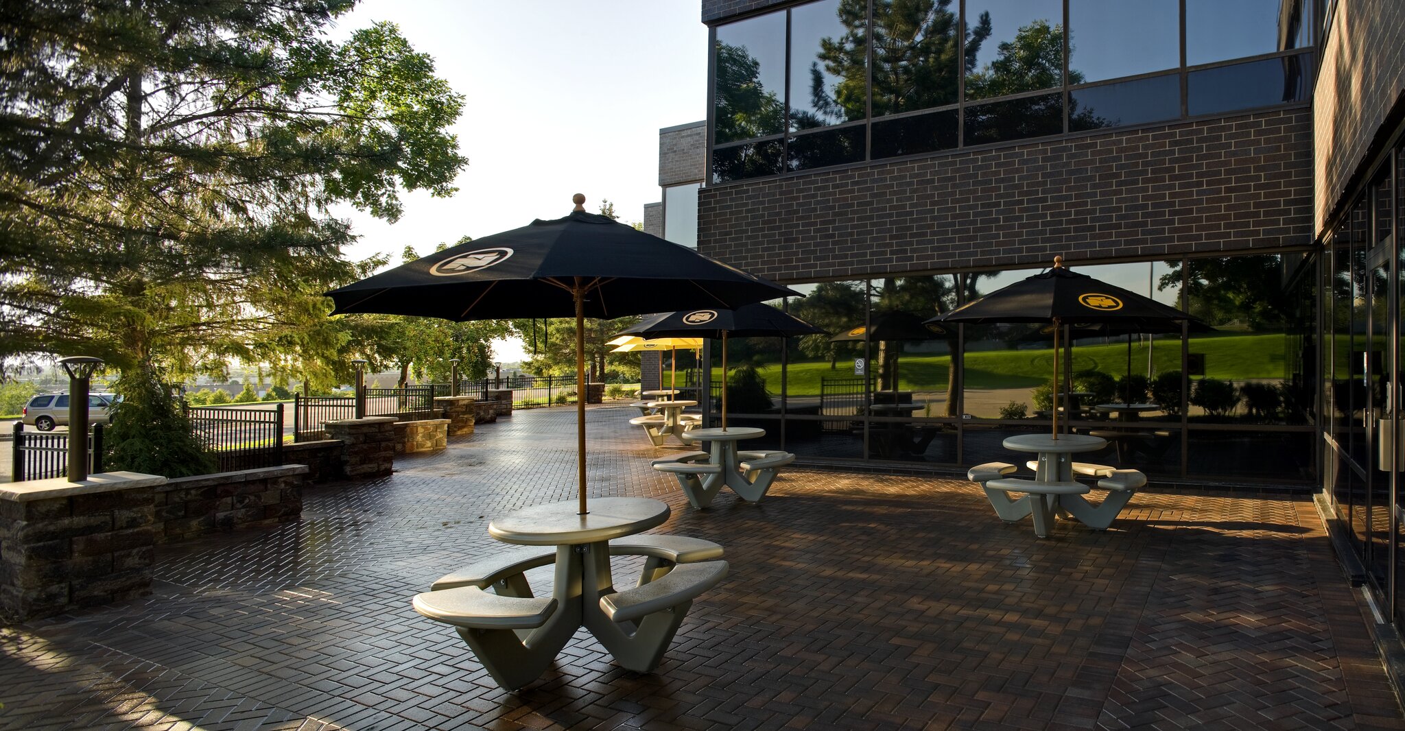 Outdoor patio with tables and umbrellas near office building.