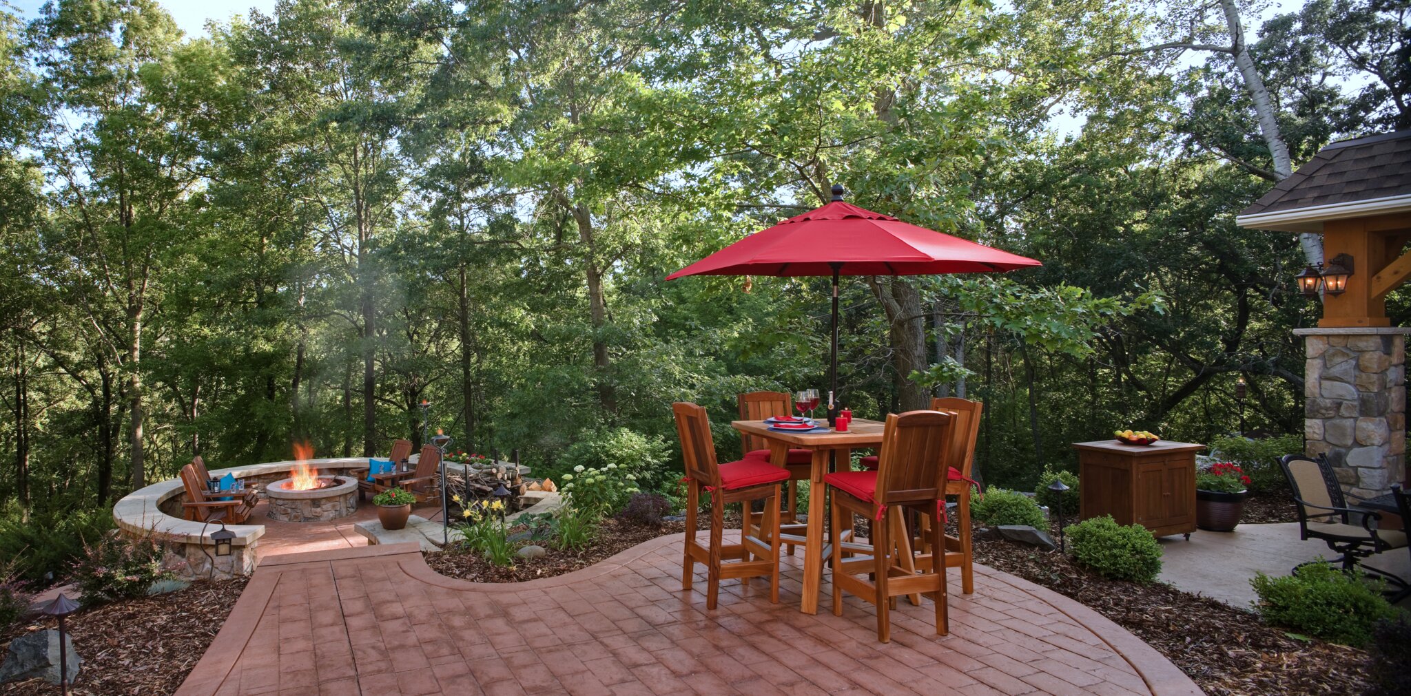 Outdoor patio with table, red umbrella, and fire pit.