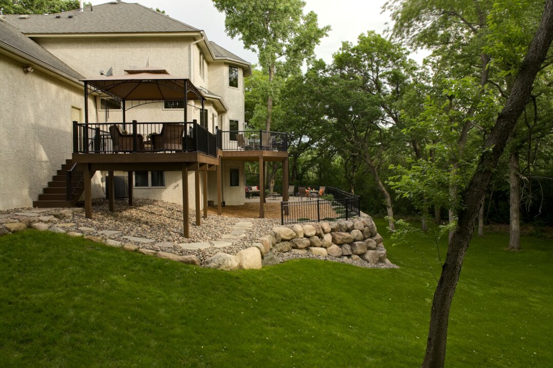 Backyard patio with wooden deck and stone landscaping.