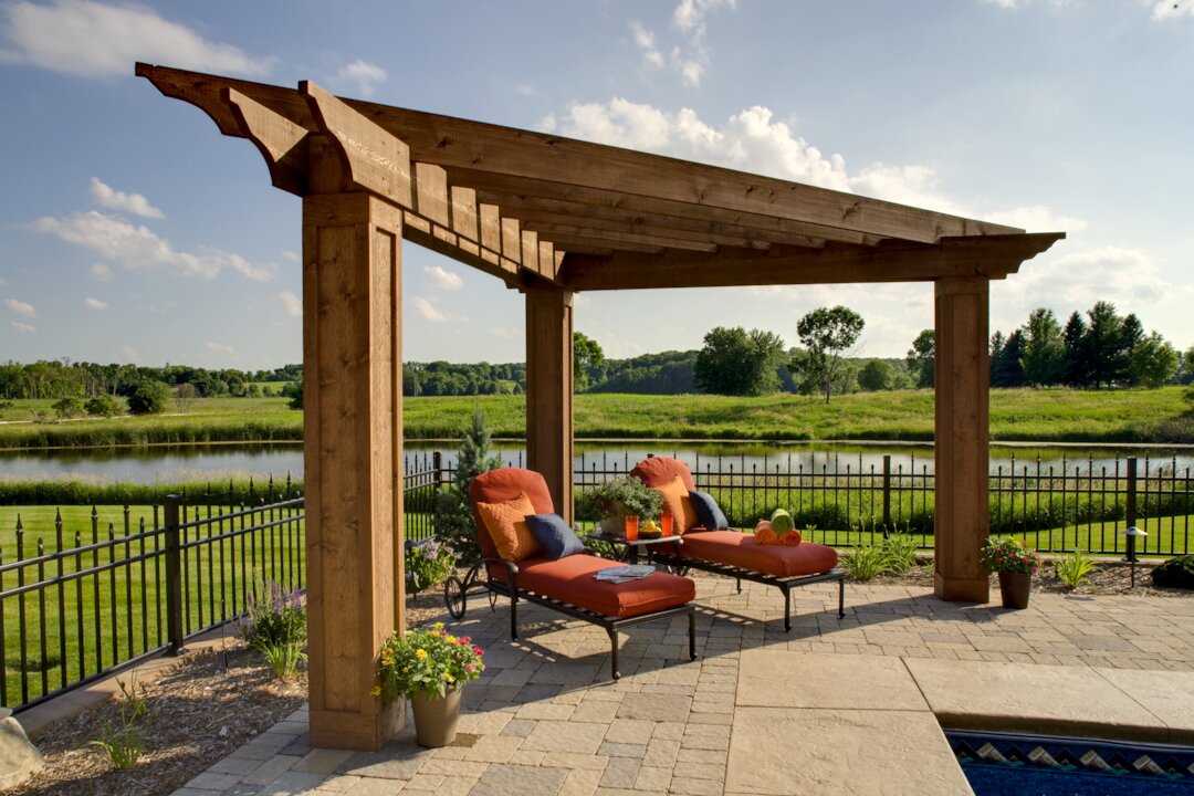 Outdoor pergola by a pond with lounge chairs.