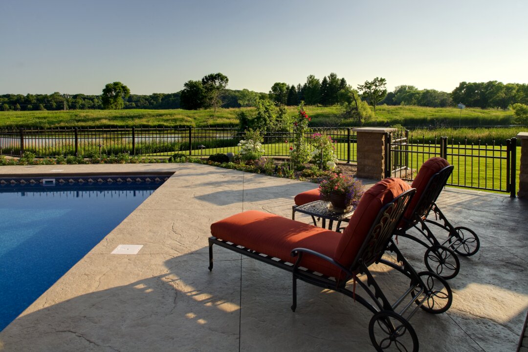 Patio chairs by pool with scenic landscape view.