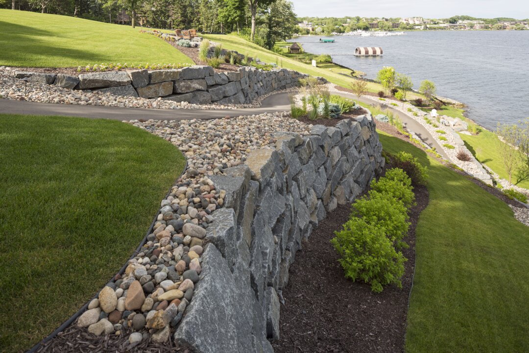 Stone retaining wall with lakeside landscape view.