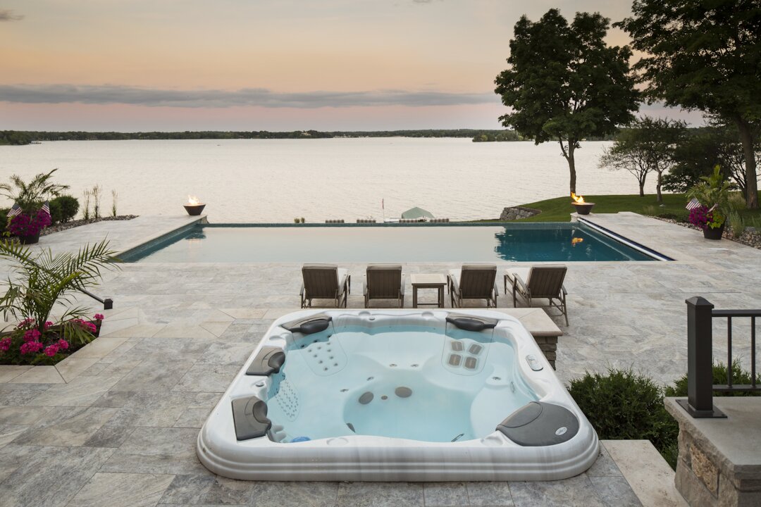 Luxury hot tub and pool overlooking serene lake.