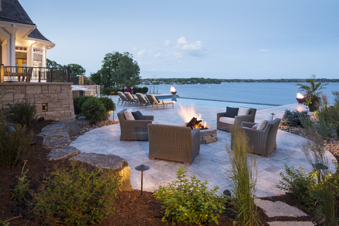 Lakeside patio with fire pit and seating area.