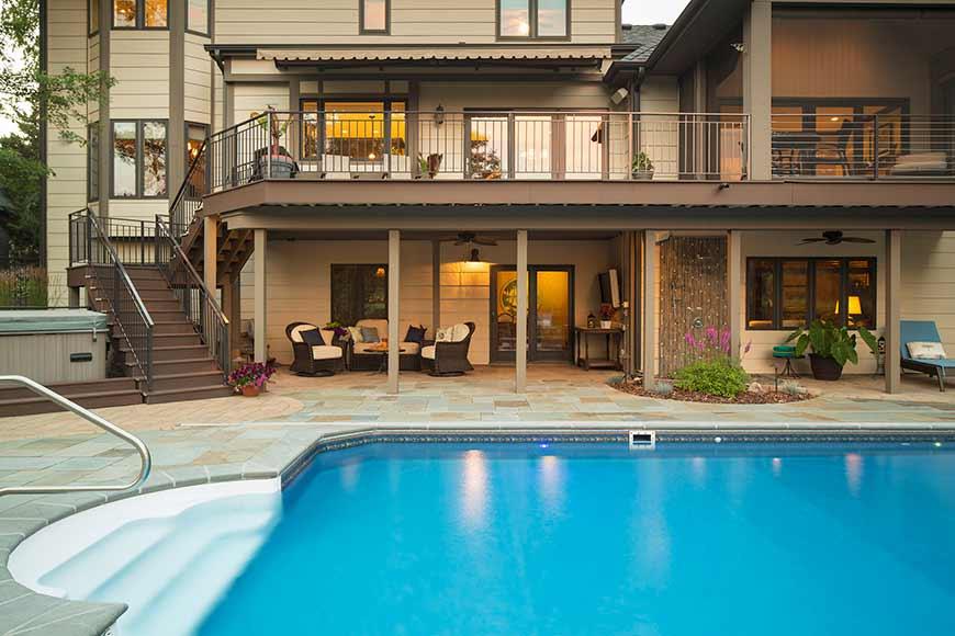 Luxury home backyard with pool and patio furniture.