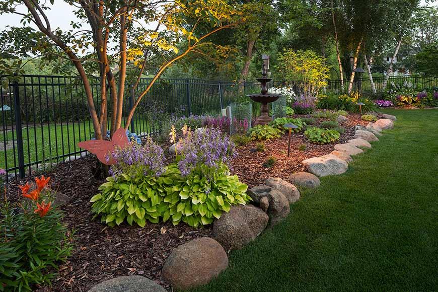 Colorful garden with flowers and stone border.