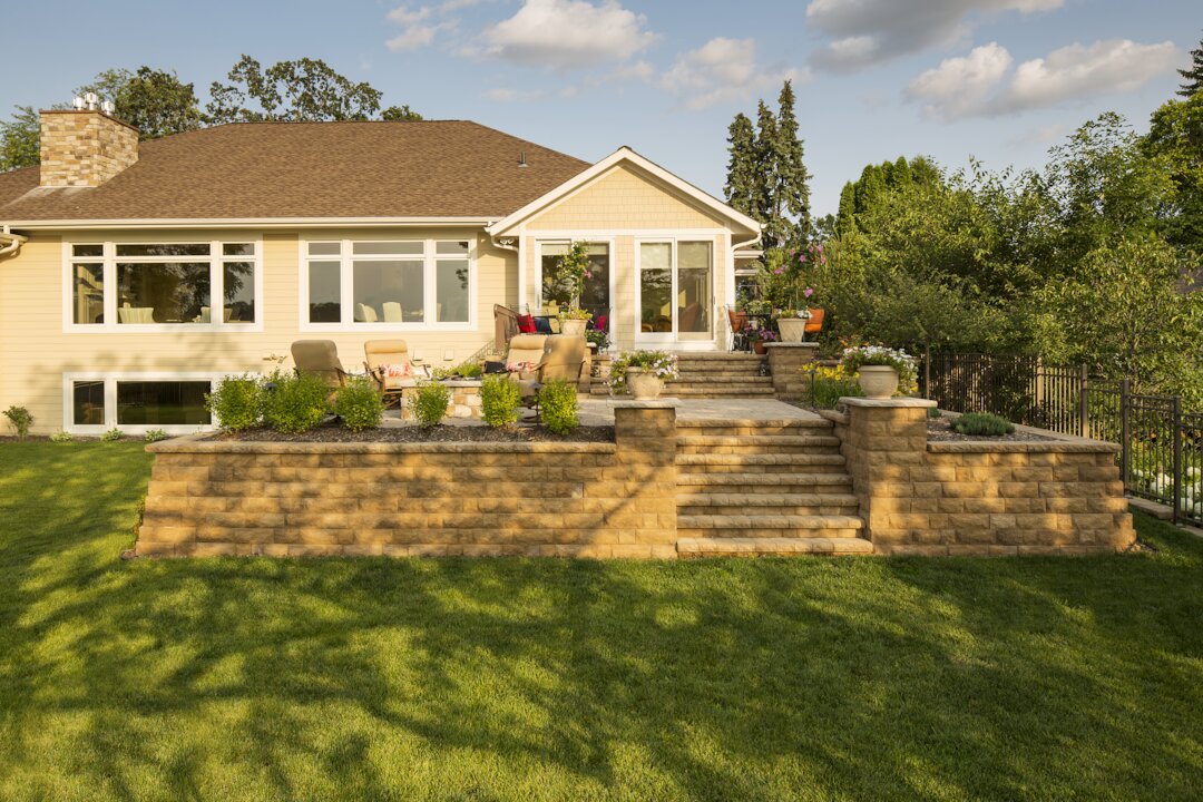 Sunny backyard patio with garden and seating area.