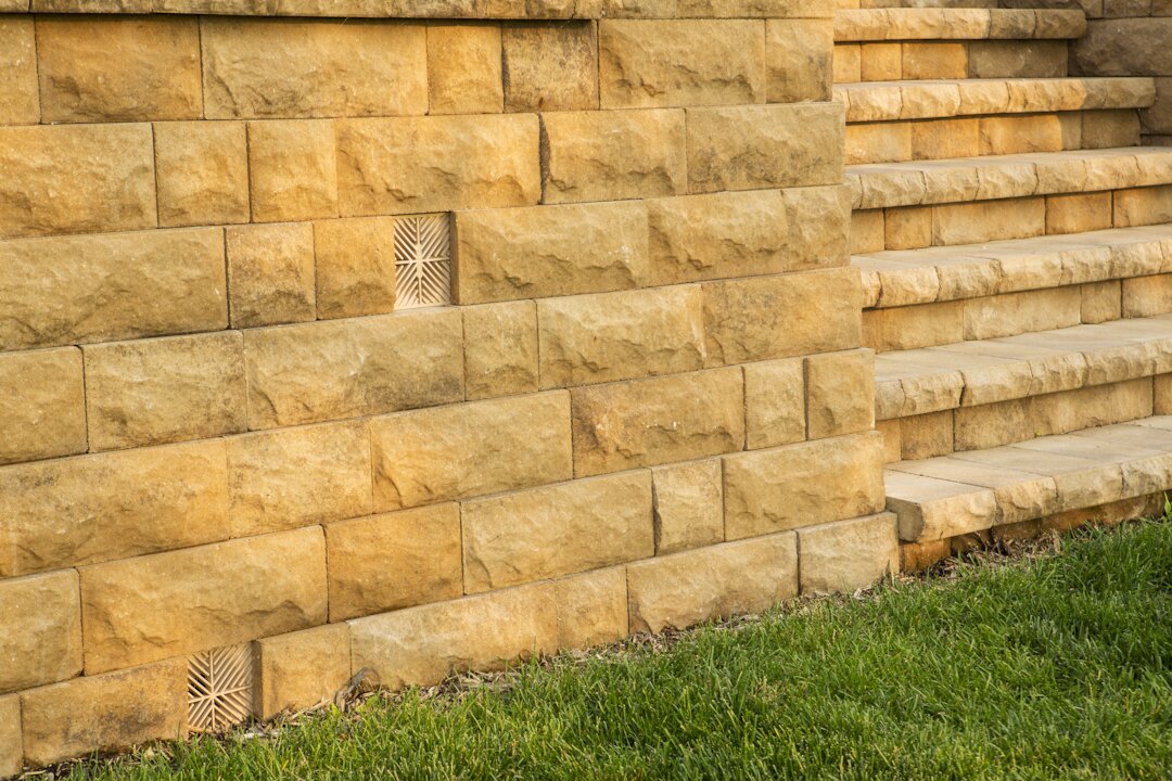 Stone retaining wall with green grass and steps