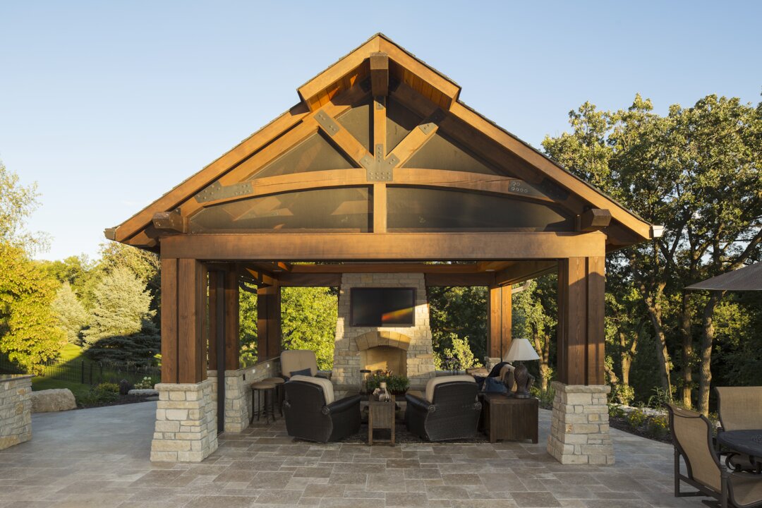 Outdoor patio with seating and fireplace, surrounded by trees.
