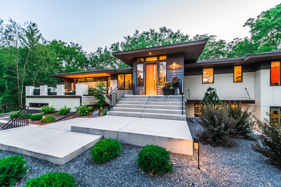 Modern house with landscaped entrance at dusk.