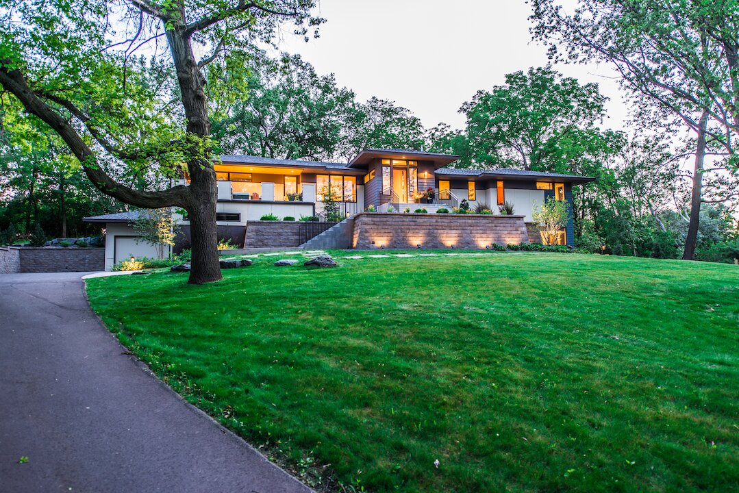 Modern house with large front yard and trees.
