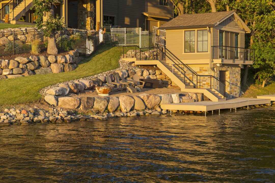 Lakeside house with stone patio and chairs