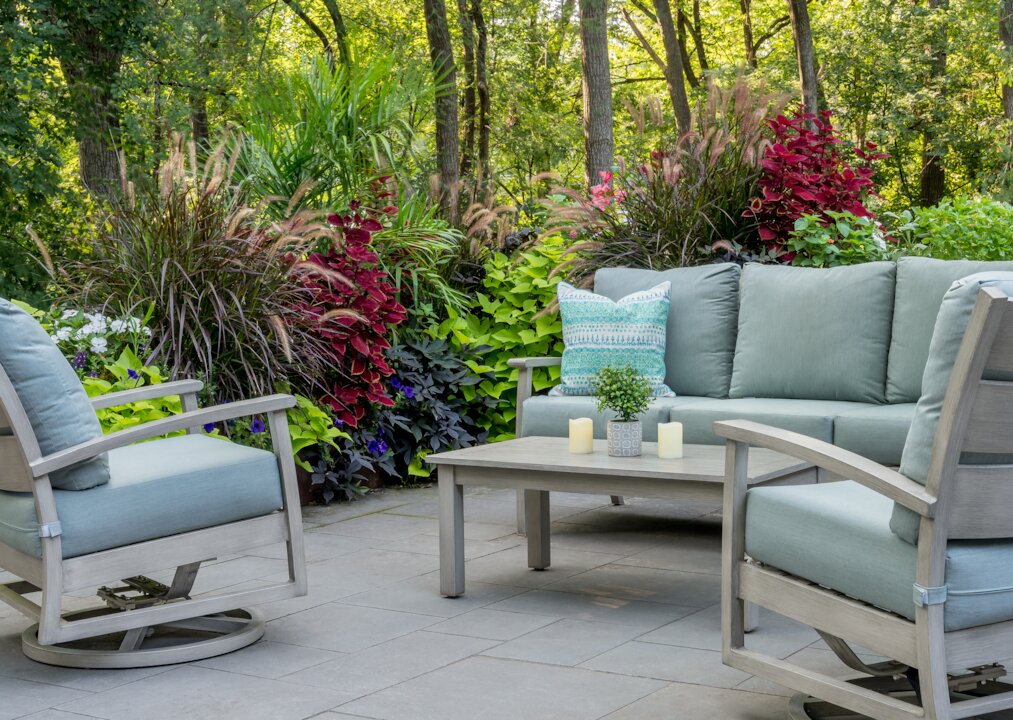 Garden patio with furniture and lush plants.