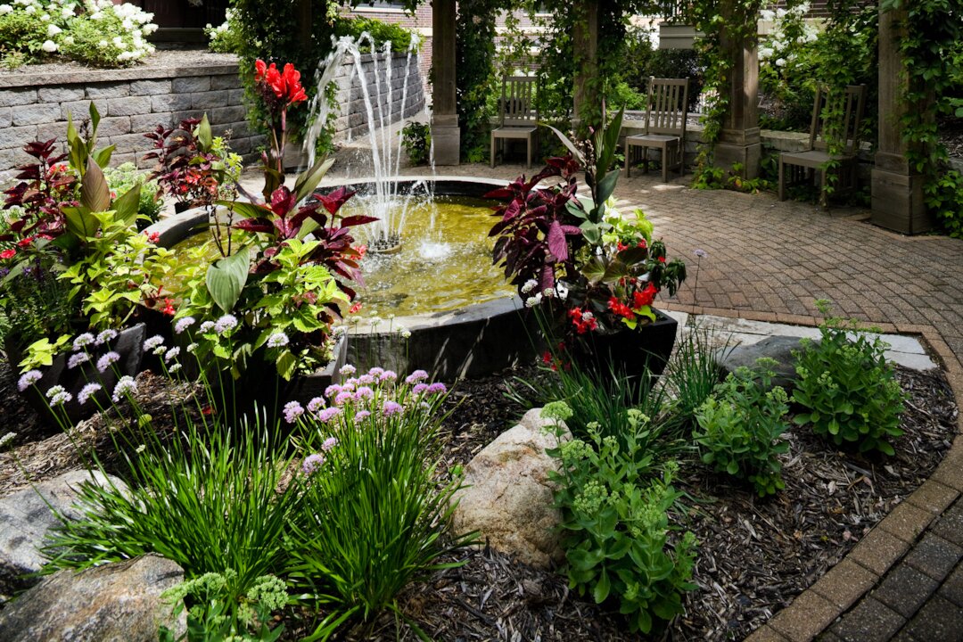 Fountain surrounded by colorful garden flowers and plants.