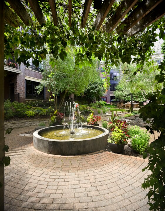 Lush garden courtyard with central fountain and plants.