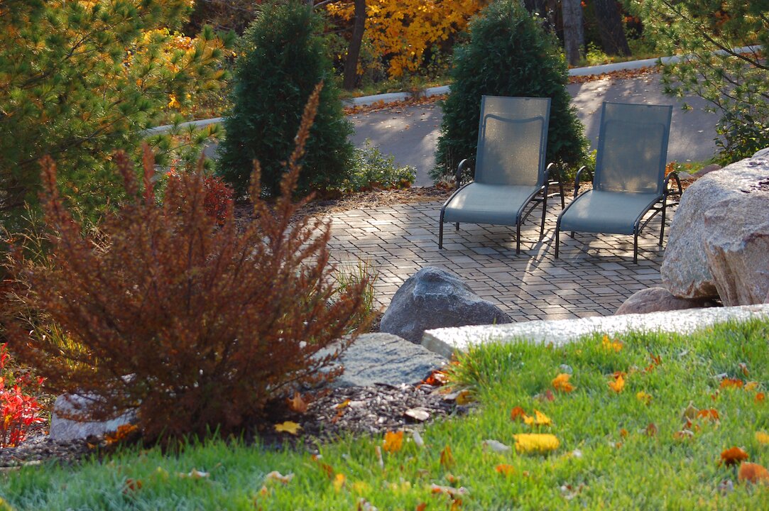 Two lounge chairs on a garden patio in fall.