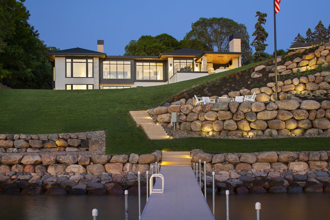 Modern lakeside house with dock and stone terrace.