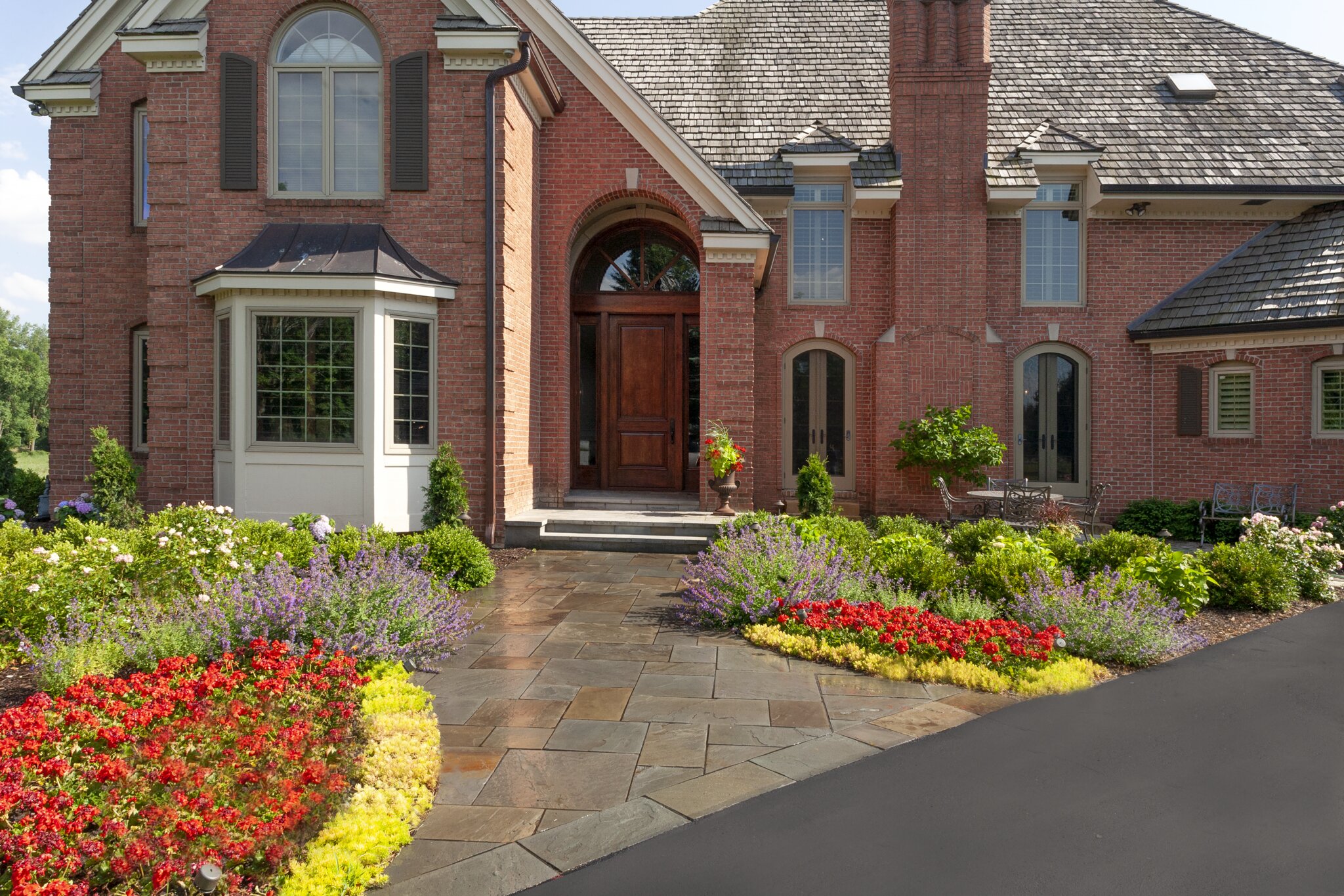 Brick house with large garden and flowers.