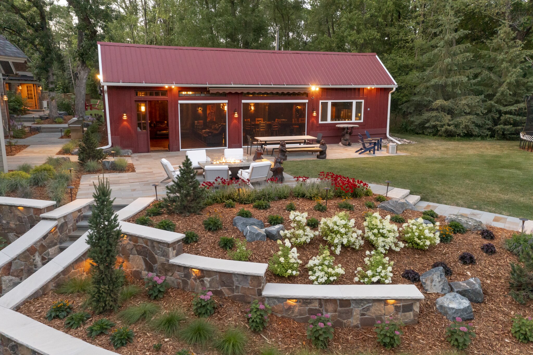 Red barn with landscaped garden and outdoor seating.