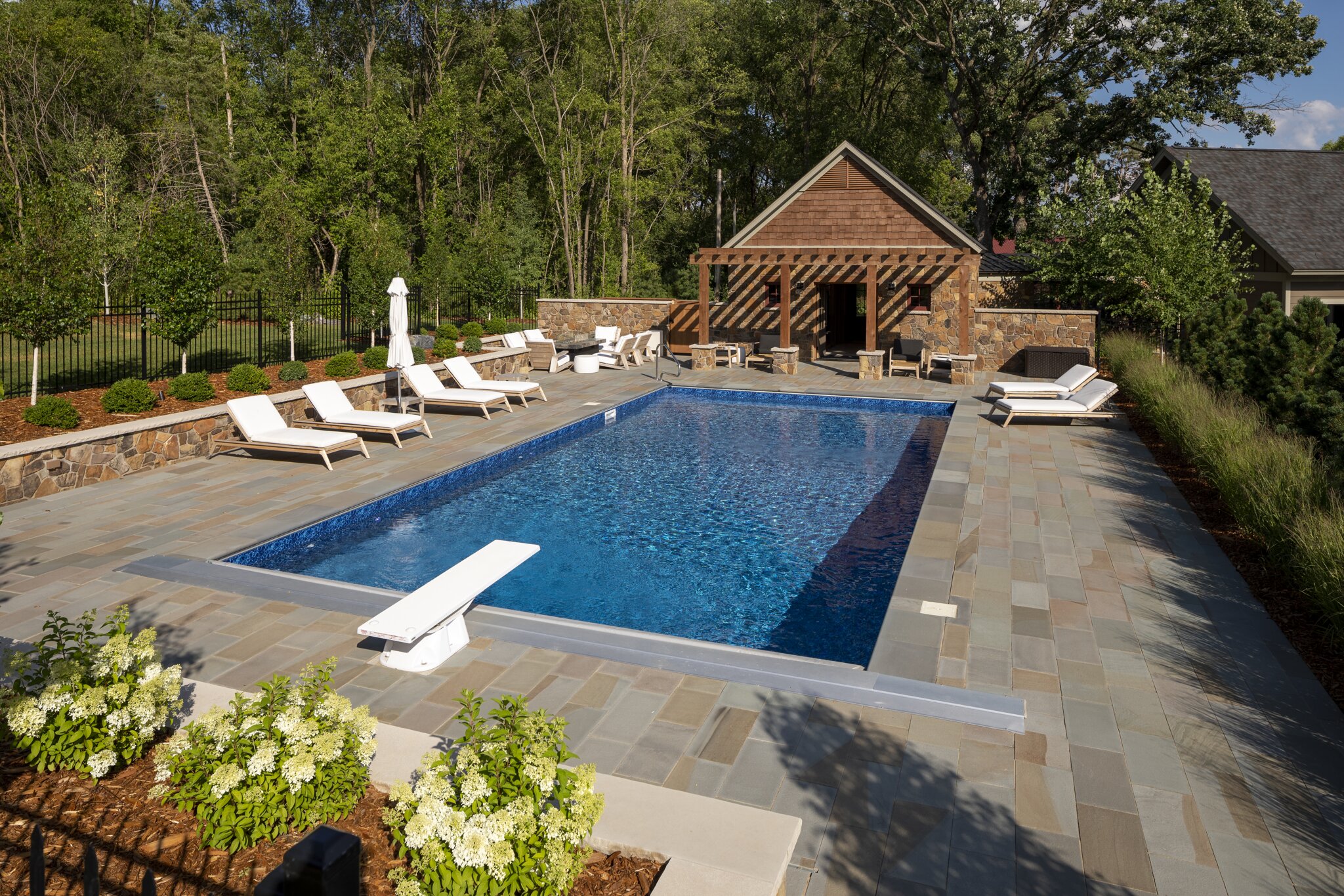 Luxurious backyard pool with lounge chairs and cabana.