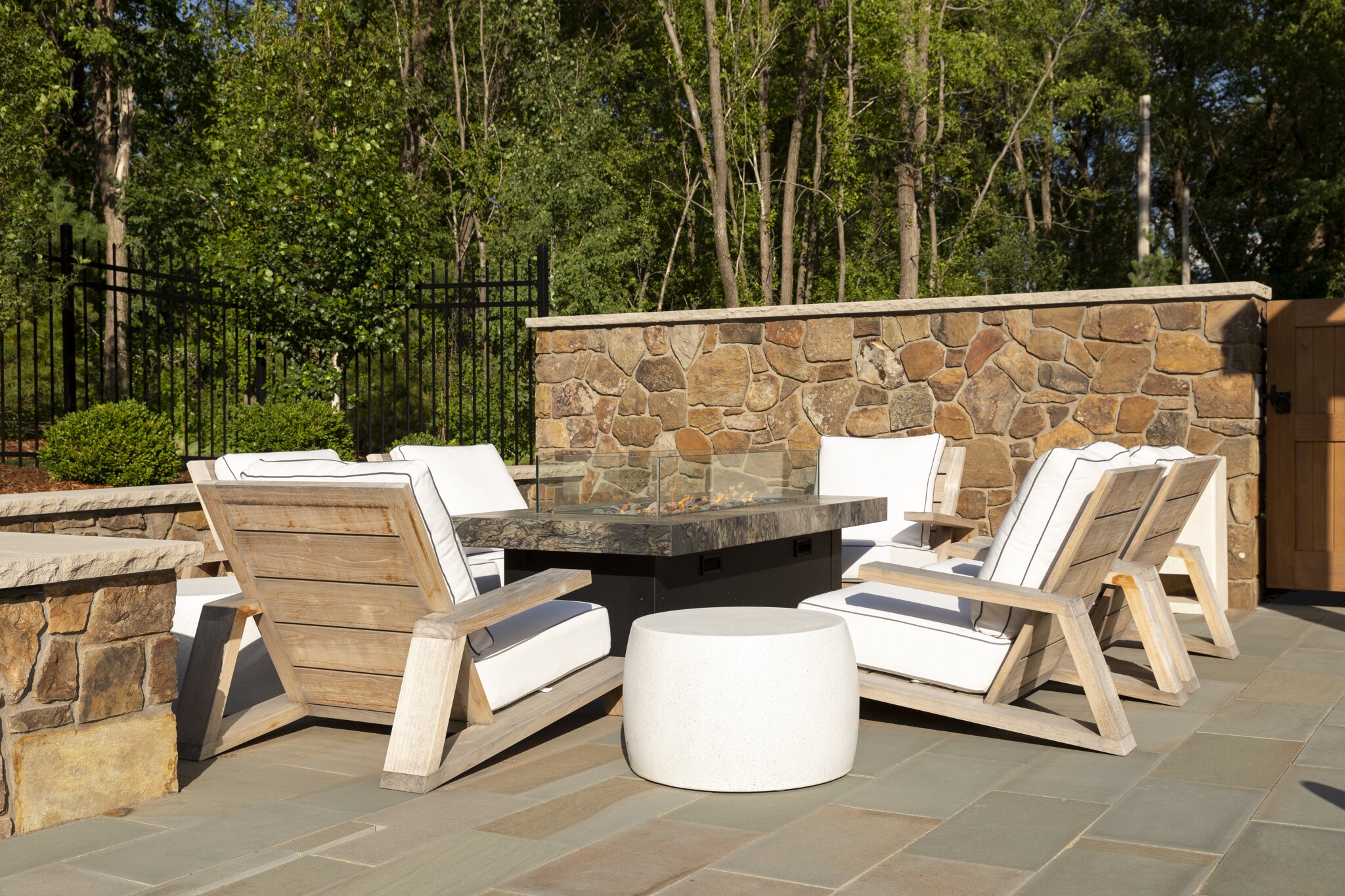 Outdoor patio with stone wall and chairs.