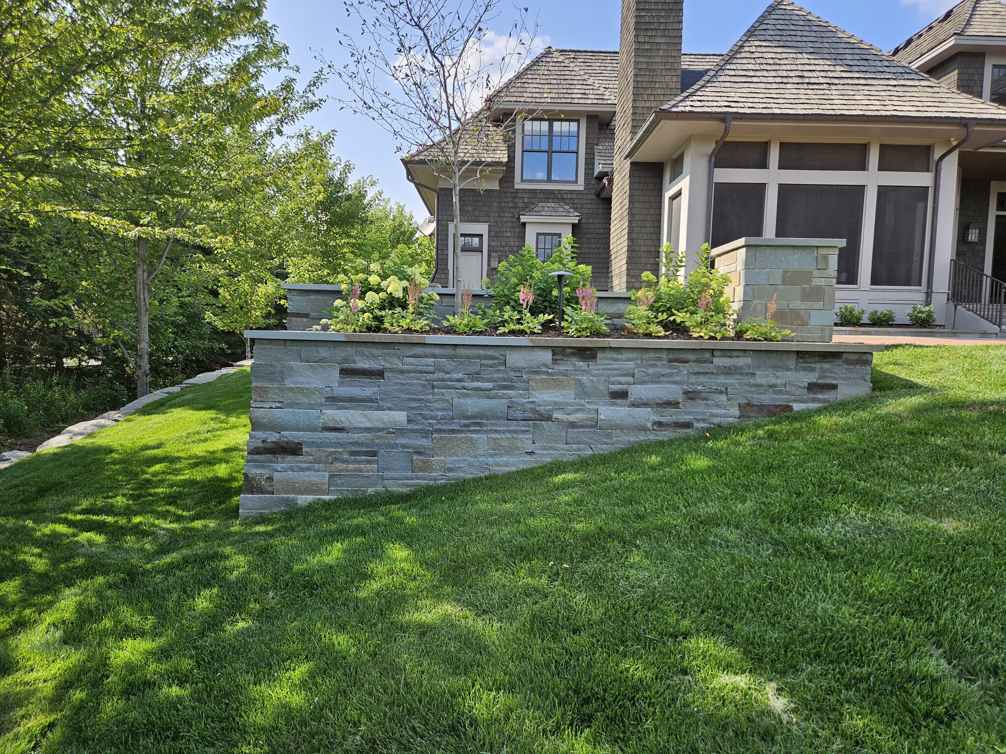 House with stone retaining wall and landscaped garden.