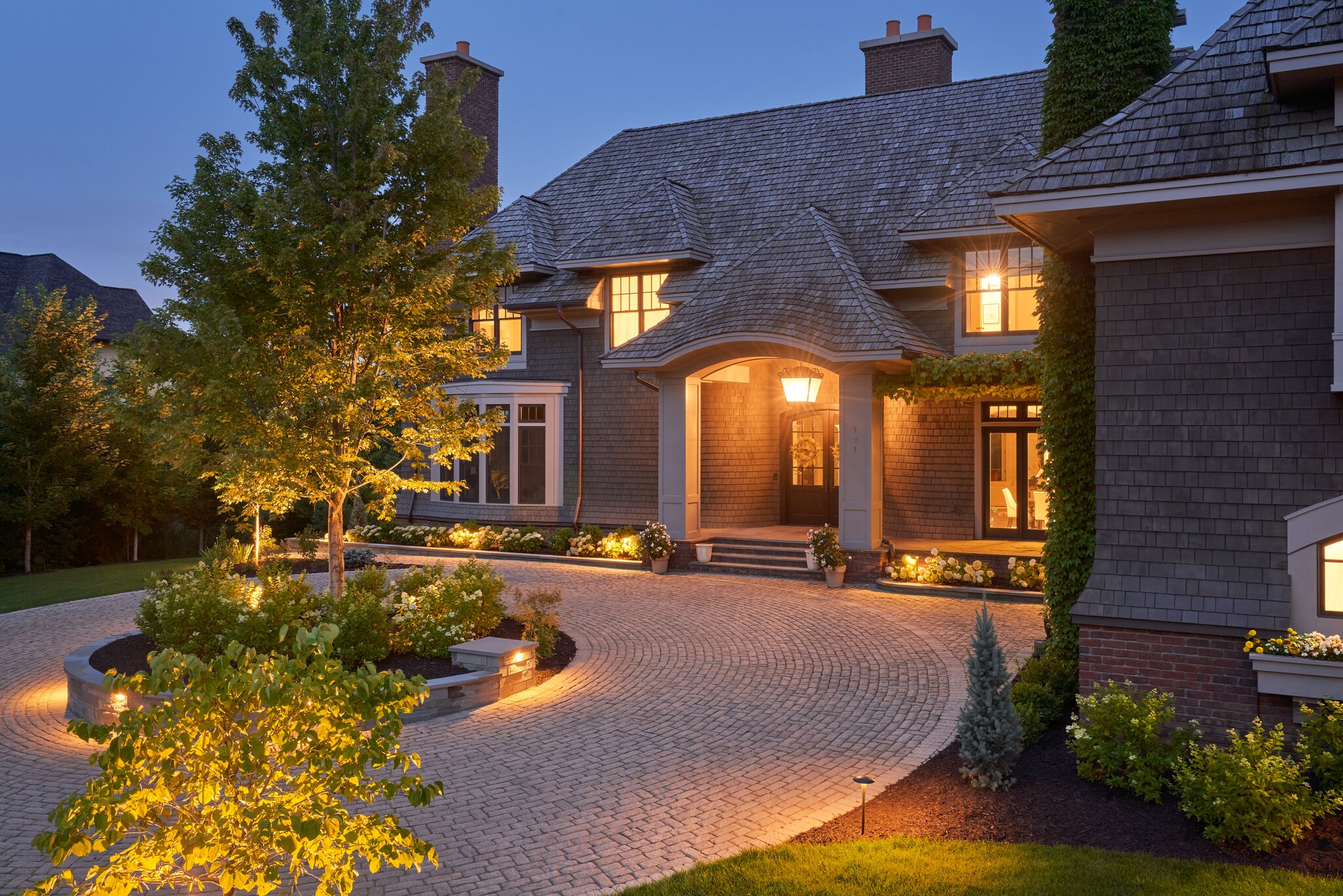 Elegant house with lit garden at dusk.