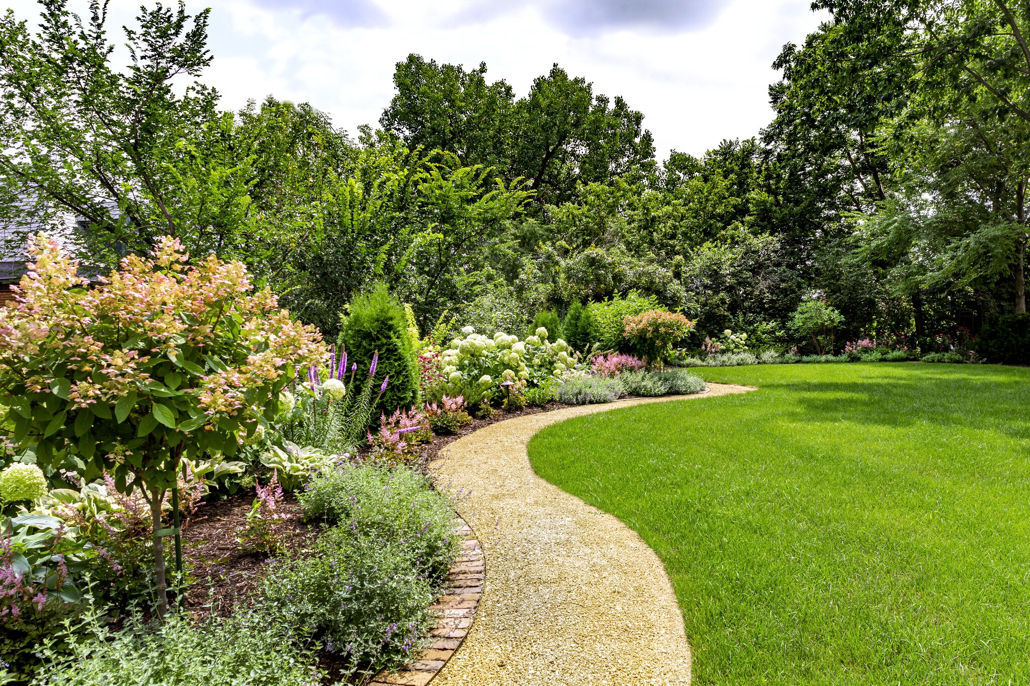 Colorful garden with curved stone pathway.