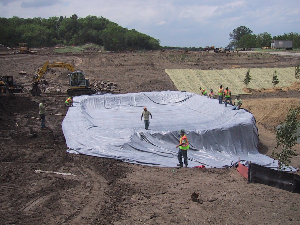 Workers installing liner in construction site pit
