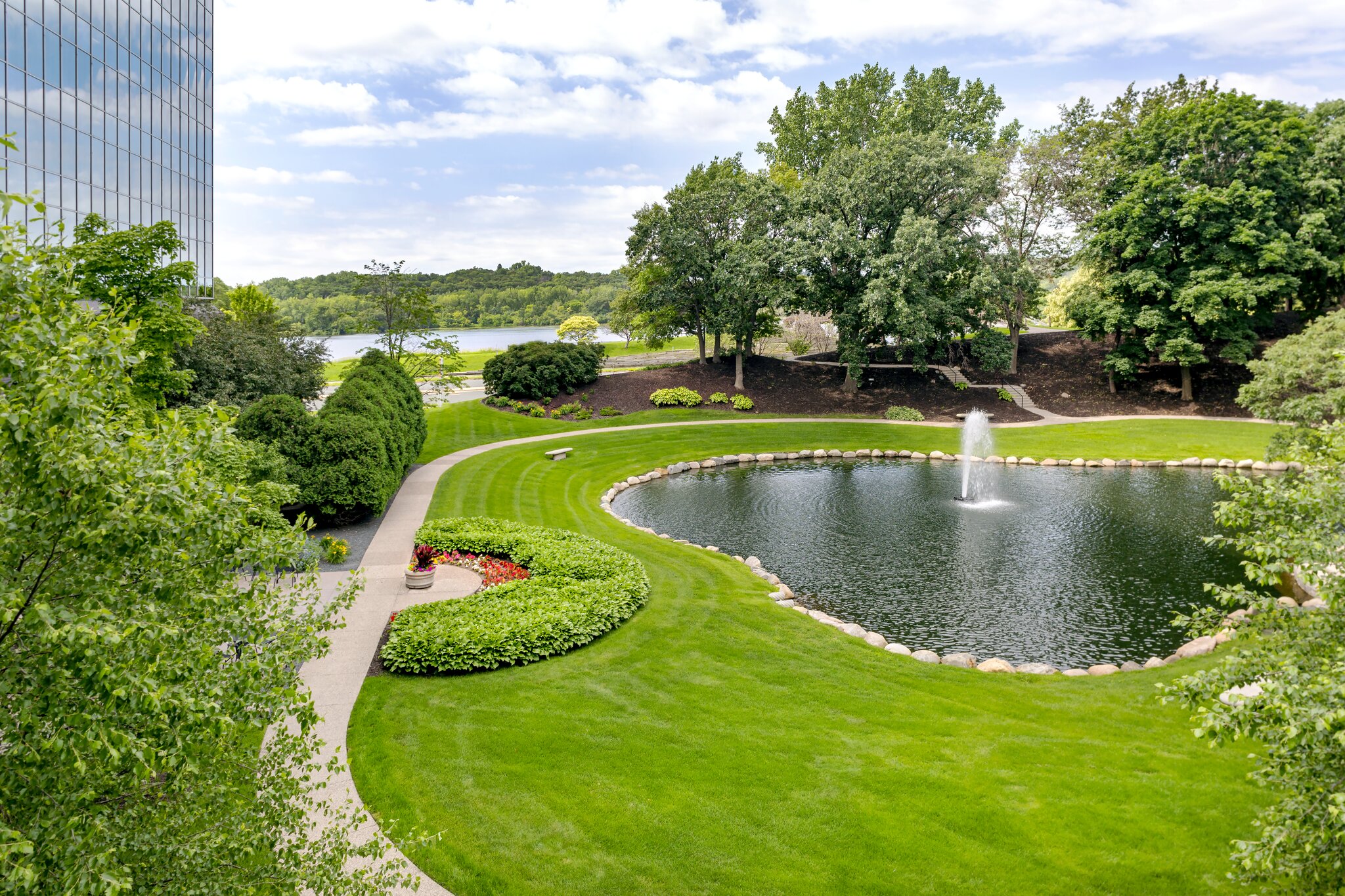 Lush garden with pond and fountain, office view.