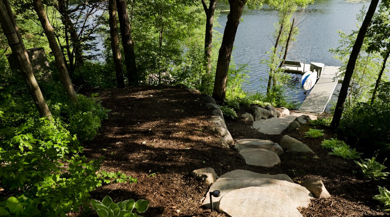 Stone path leading to lakeside dock and forest