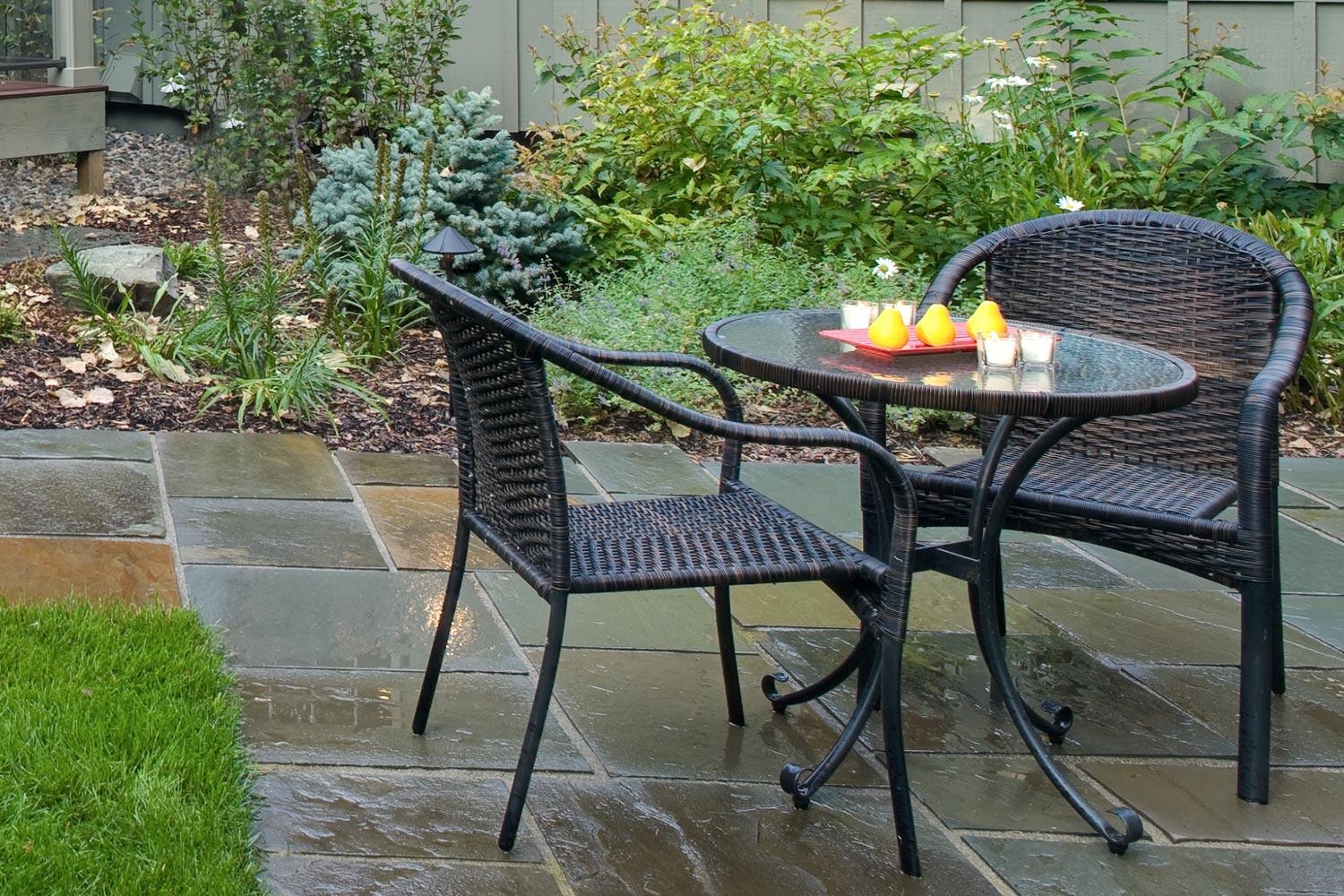 Patio table and chairs on wet slate tiles.
