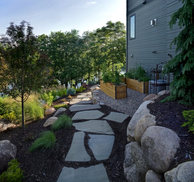 Stone pathway through landscaped garden beside house.
