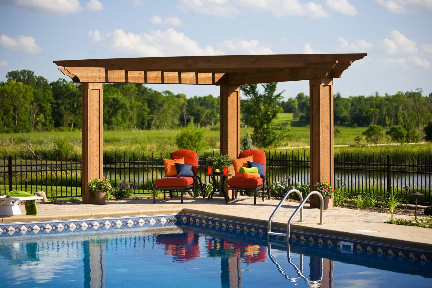 Outdoor poolside seating with pergola and nature view.