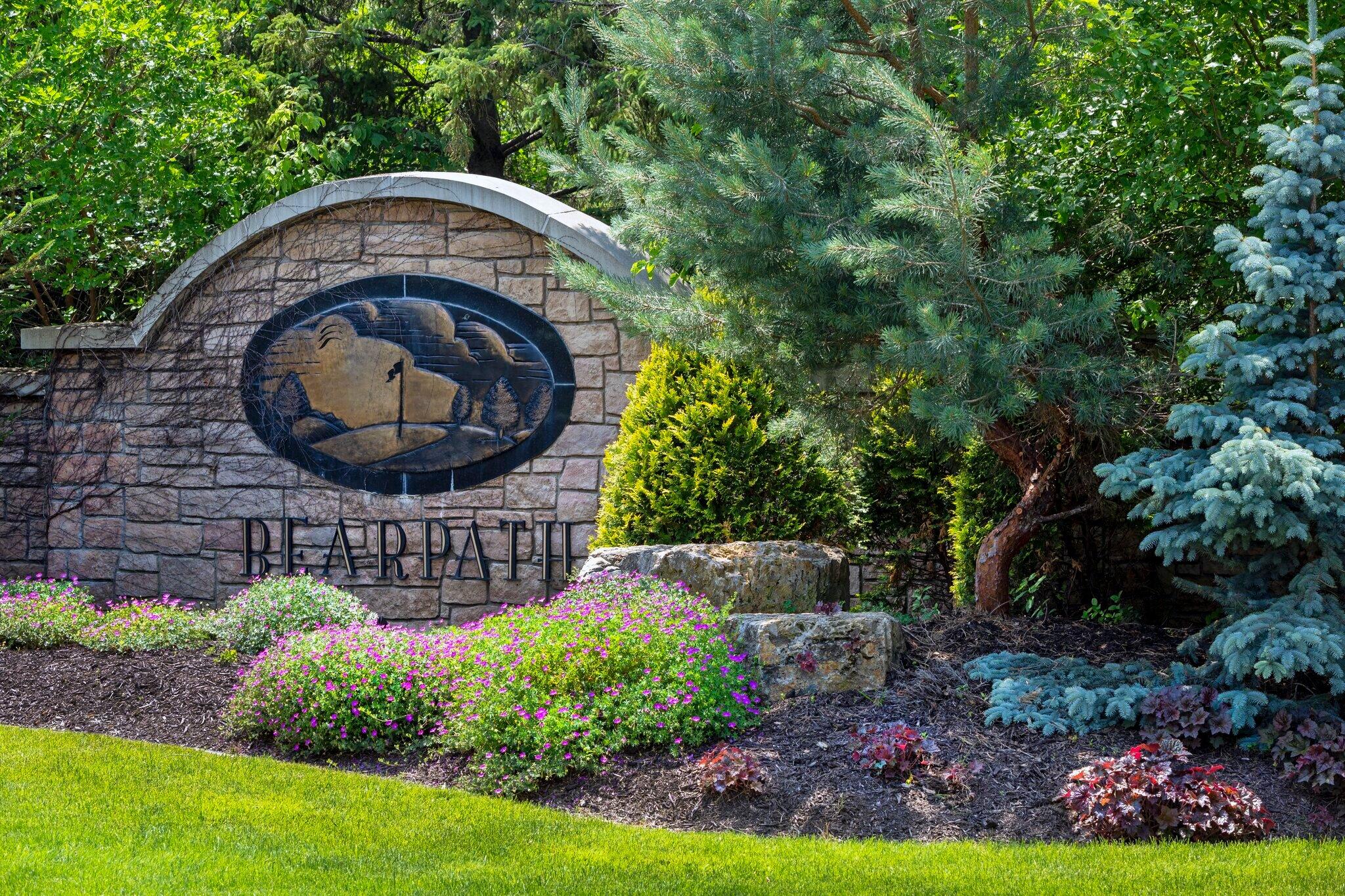 Bearpath stone sign surrounded by trees and flowers.