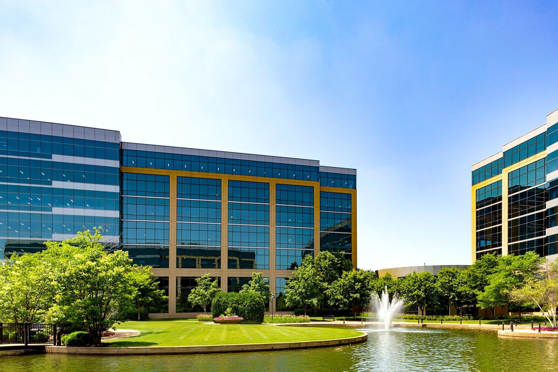 Modern office buildings with fountain and greenery.