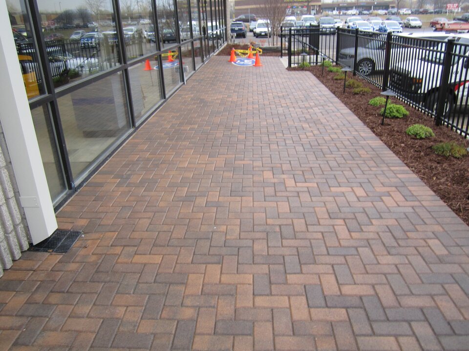 Brick paver walkway by parking lot and building.