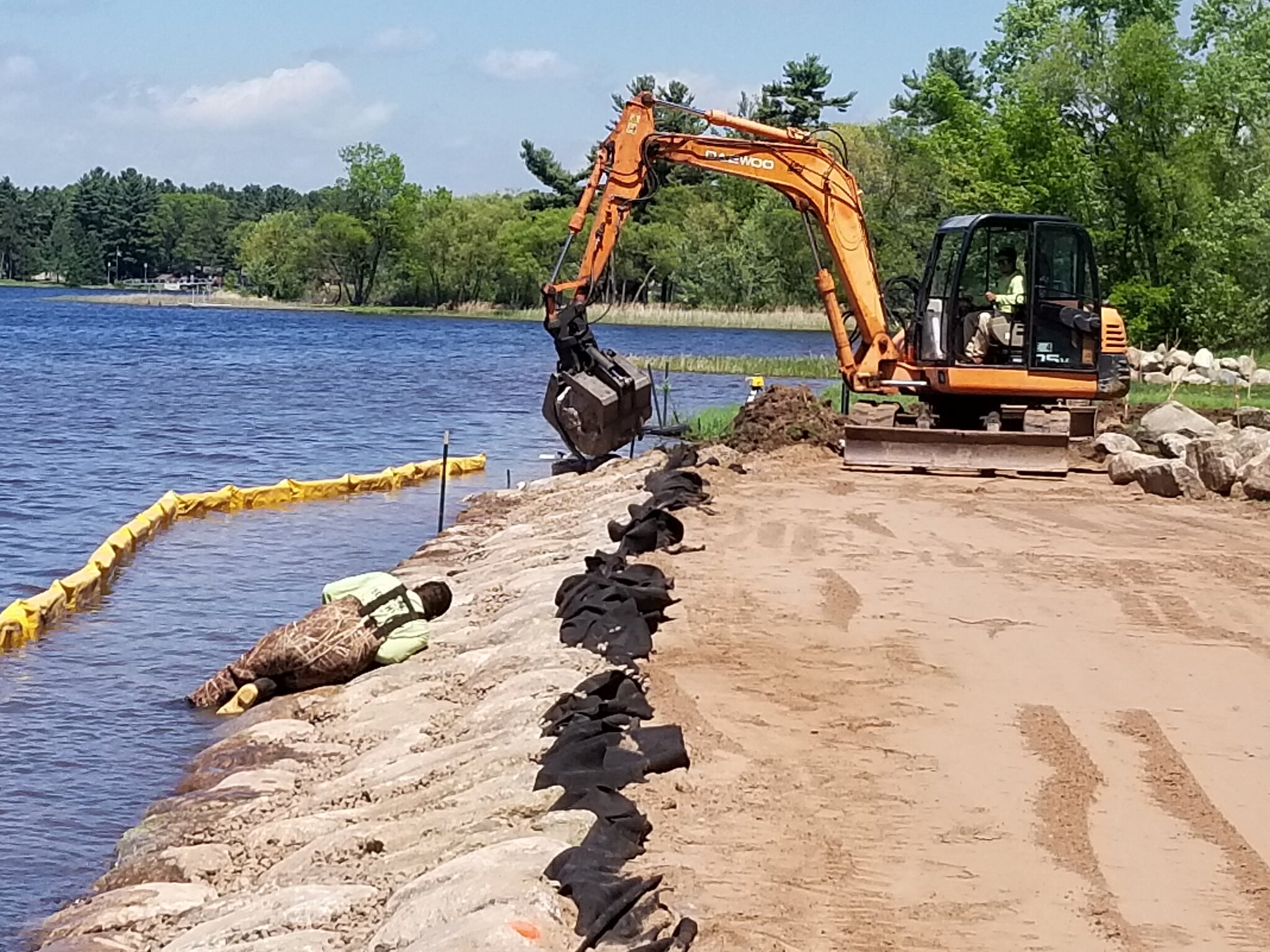 Excavator working on lakeside construction project.