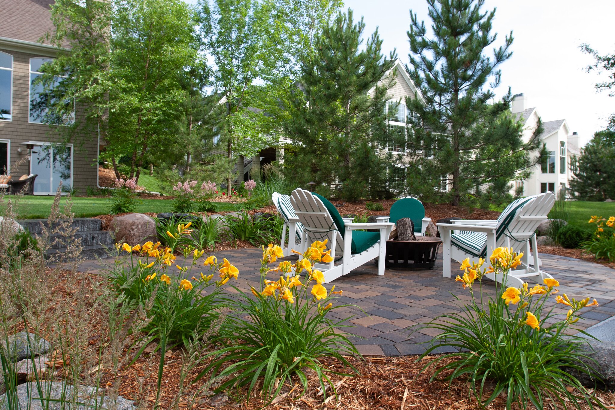 Backyard patio with chairs and yellow flowers.
