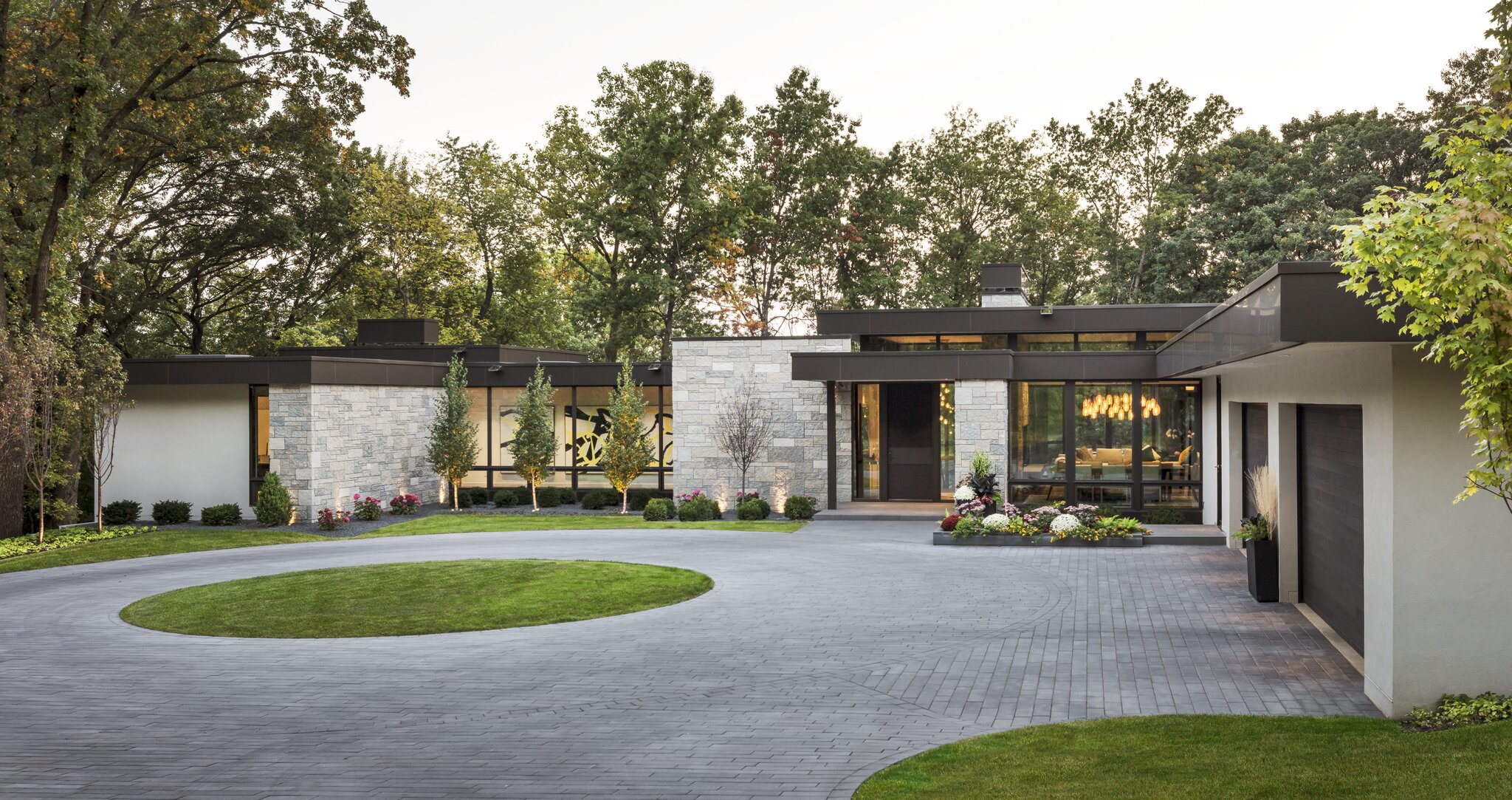 Modern home with circular driveway and large windows.