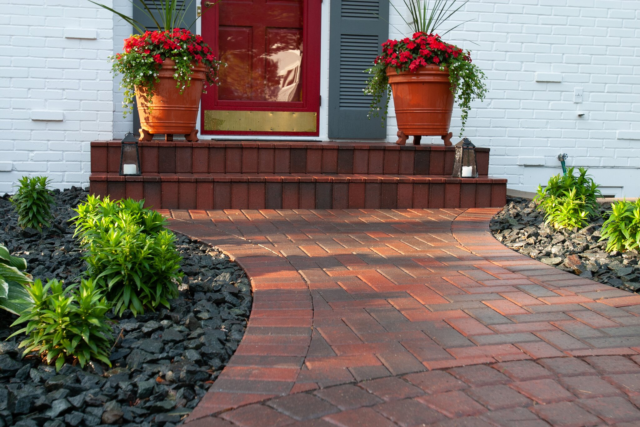 Brick walkway with potted red flowers