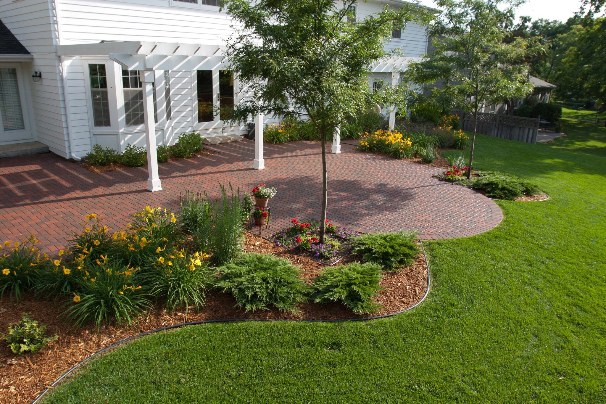 Brick patio with garden and flowers in backyard.