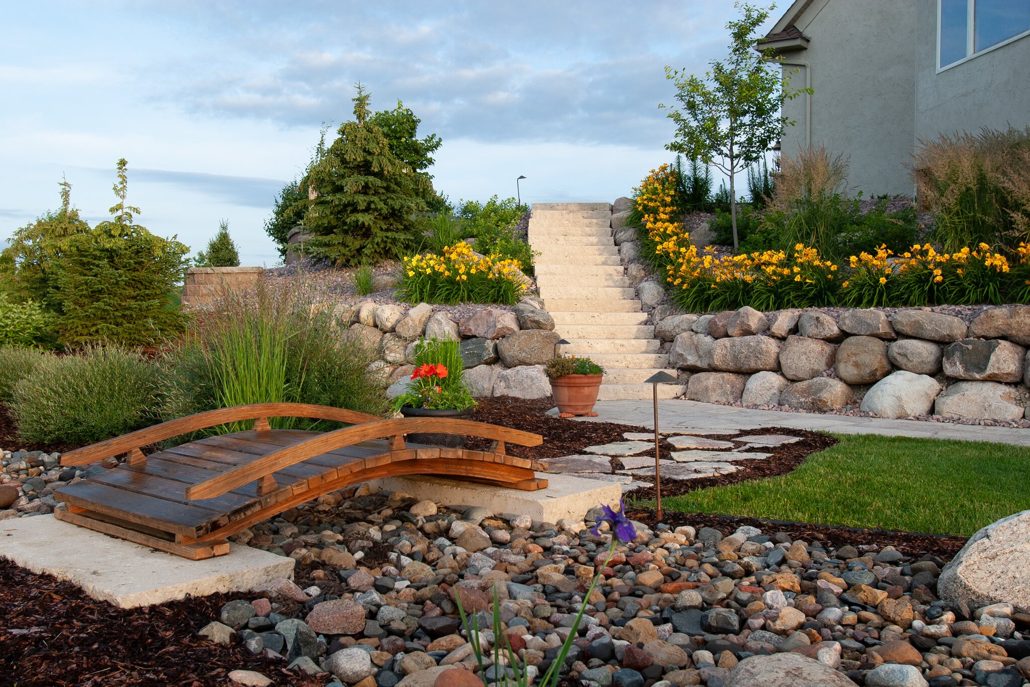 Garden with stone stairs and wooden bridge.