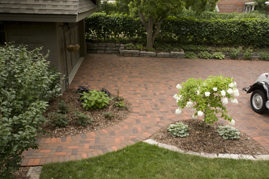 Brick driveway with garden and trees