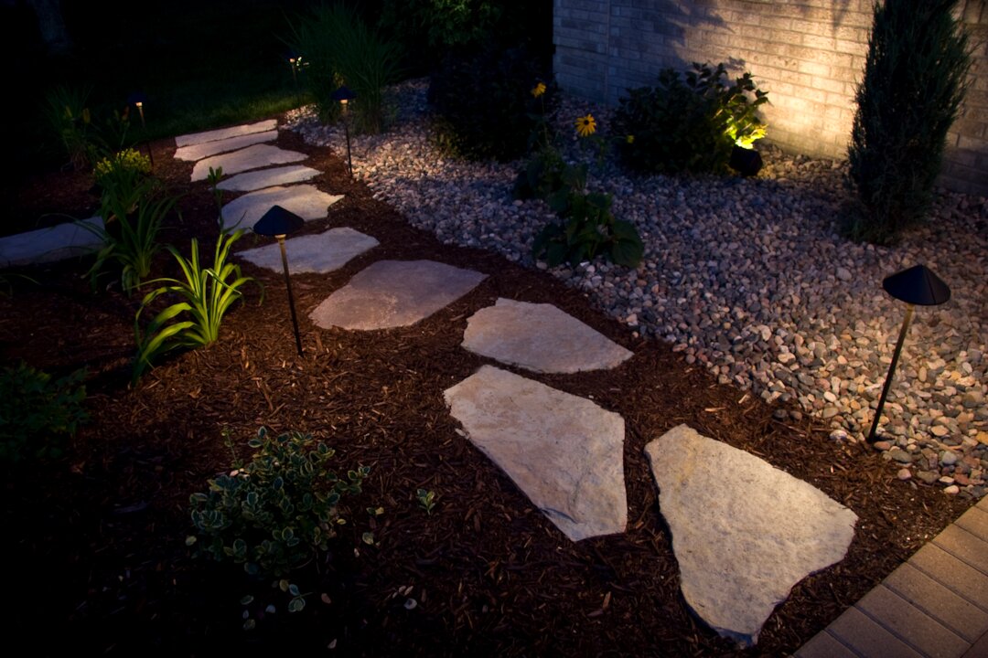 Outdoor pathway with stones and garden lights at night.