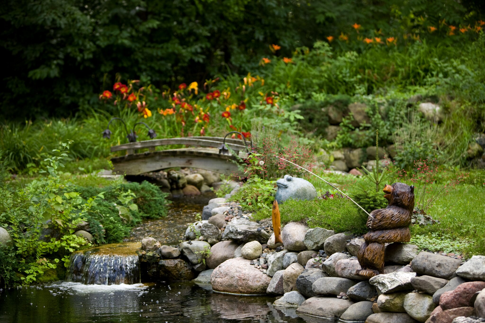 Garden pond with bridge and bear statue.