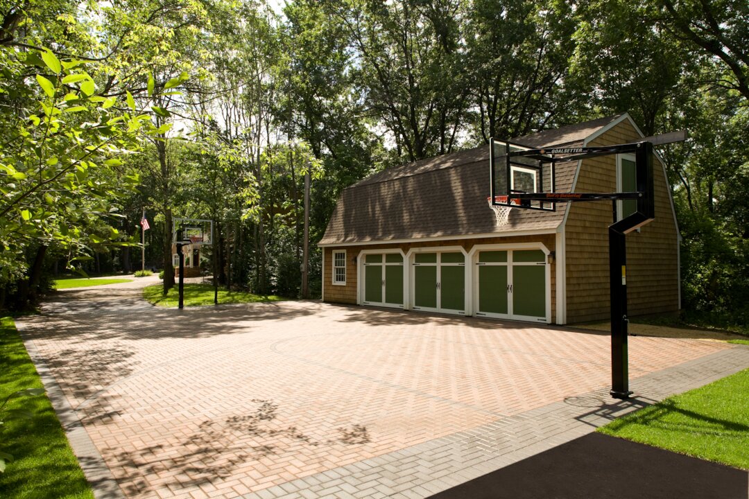 Outdoor basketball court beside green garage.