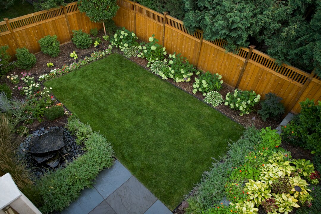 Beautiful backyard garden with green lawn and flowers.